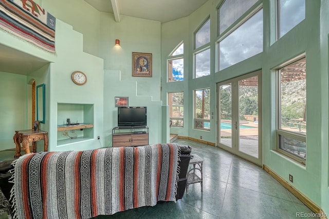 living room featuring plenty of natural light, beamed ceiling, and a towering ceiling