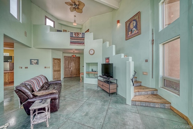 living room with ceiling fan and a towering ceiling