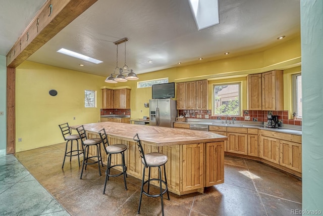 kitchen with hanging light fixtures, a center island, appliances with stainless steel finishes, a kitchen bar, and tasteful backsplash