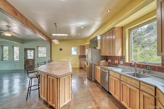 kitchen with backsplash, stainless steel appliances, sink, ceiling fan, and pendant lighting