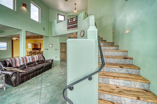 staircase featuring ceiling fan, tile patterned floors, and a high ceiling