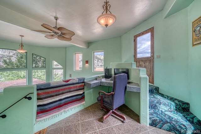 office with tile patterned flooring, built in desk, ceiling fan, and a healthy amount of sunlight