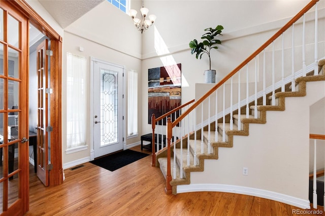 entrance foyer featuring baseboards, a chandelier, stairway, a high ceiling, and wood finished floors