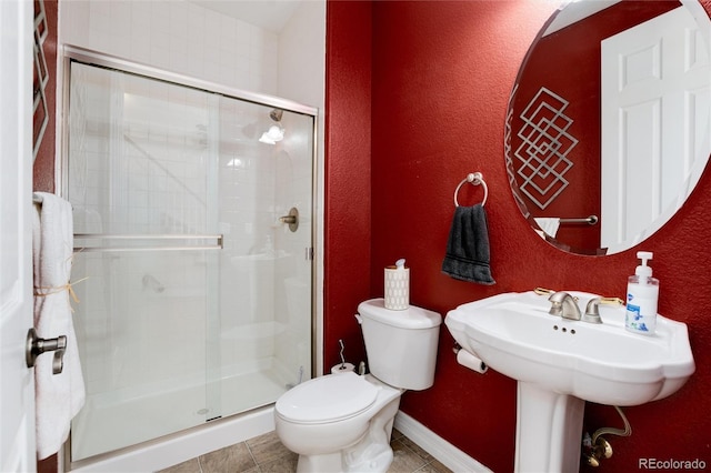 bathroom with tile patterned floors, toilet, a shower stall, and baseboards