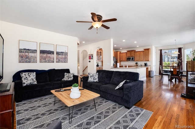 living room featuring recessed lighting, arched walkways, light wood finished floors, and ceiling fan