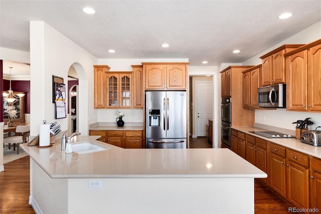 kitchen featuring dark wood-style flooring, recessed lighting, appliances with stainless steel finishes, arched walkways, and a sink