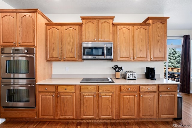 kitchen with wood finished floors, light countertops, a toaster, and stainless steel appliances