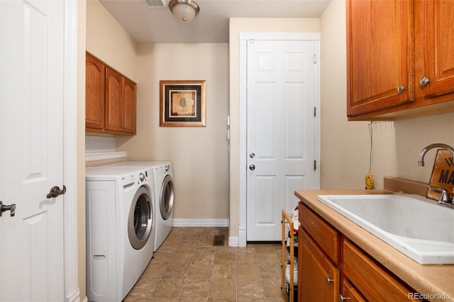 clothes washing area featuring visible vents, washing machine and dryer, a sink, baseboards, and cabinet space