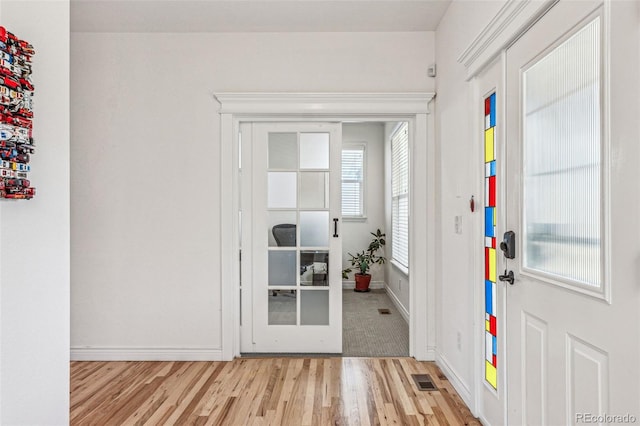 foyer entrance featuring visible vents, baseboards, and wood finished floors