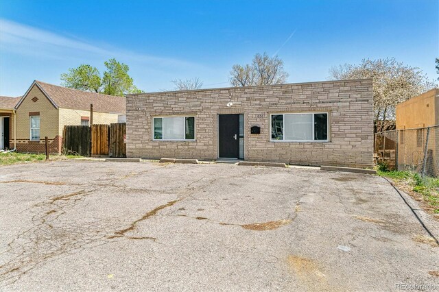 1050 S Quitman St, Denver, CO 80219 - view of front of house featuring uncovered parking, fence, and stone siding