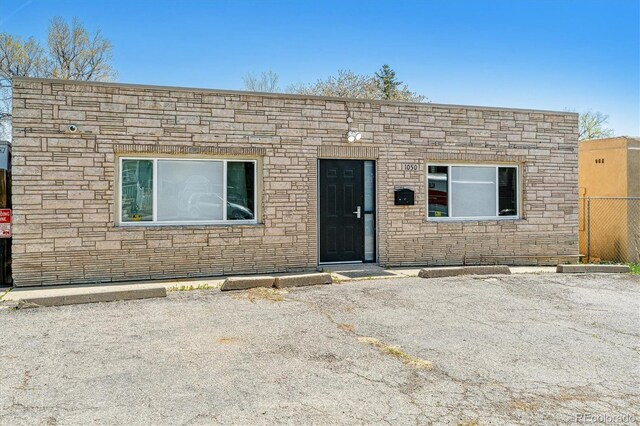 1050 S Quitman St, Denver, CO 80219 - view of front facade featuring uncovered parking, fence, and stone siding