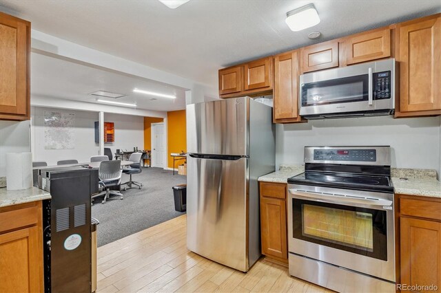 1050 S Quitman St, Denver, CO 80219 - kitchen with brown cabinets, light wood-style floors, light stone countertops, and stainless steel appliances