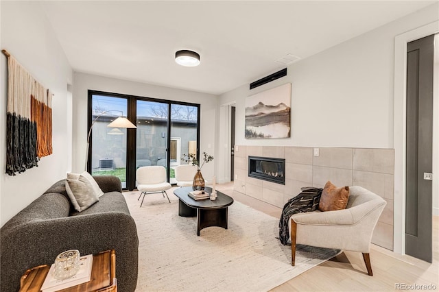 living room featuring wood-type flooring and a tiled fireplace