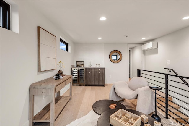 sitting room with indoor wet bar, light wood-type flooring, beverage cooler, and a wall mounted AC