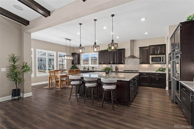 228 Rogers Ct, Castle Rock, CO 80104 - kitchen featuring wall chimney range hood, appliances with stainless steel finishes, a kitchen island, backsplash, and dark wood-style flooring