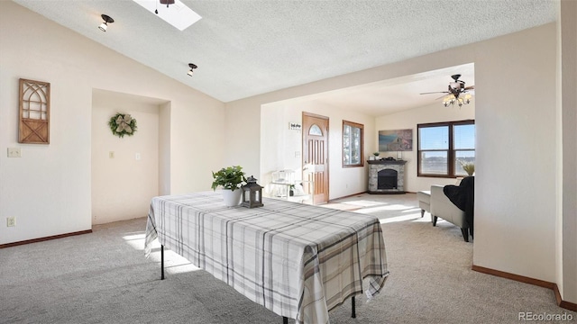 carpeted bedroom with a textured ceiling and vaulted ceiling with skylight