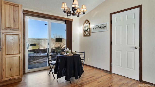 dining area featuring a textured ceiling, light hardwood / wood-style floors, and a chandelier