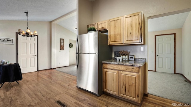 kitchen featuring vaulted ceiling with beams, an inviting chandelier, light wood-type flooring, stainless steel refrigerator, and pendant lighting