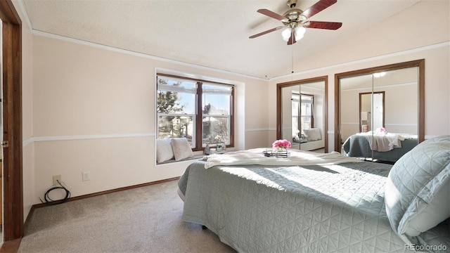 bedroom featuring lofted ceiling, ceiling fan, multiple closets, crown molding, and light carpet