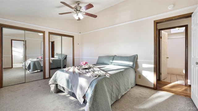 carpeted bedroom with lofted ceiling, two closets, ceiling fan, and french doors