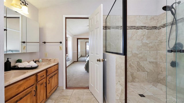 bathroom with tile patterned flooring, vanity, lofted ceiling, and tiled shower