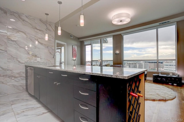 kitchen with a healthy amount of sunlight, a kitchen island with sink, sink, and pendant lighting