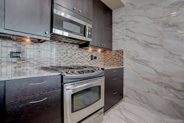 kitchen featuring tasteful backsplash, light stone countertops, dark brown cabinets, and appliances with stainless steel finishes