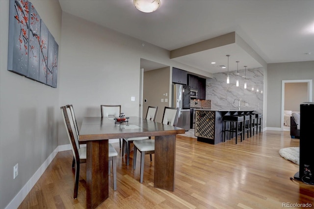 dining area with bar and light hardwood / wood-style flooring