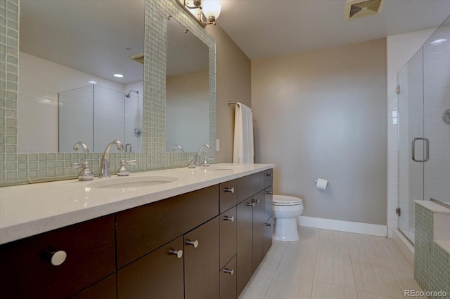 bathroom featuring vanity, a shower with door, tile patterned flooring, toilet, and tasteful backsplash