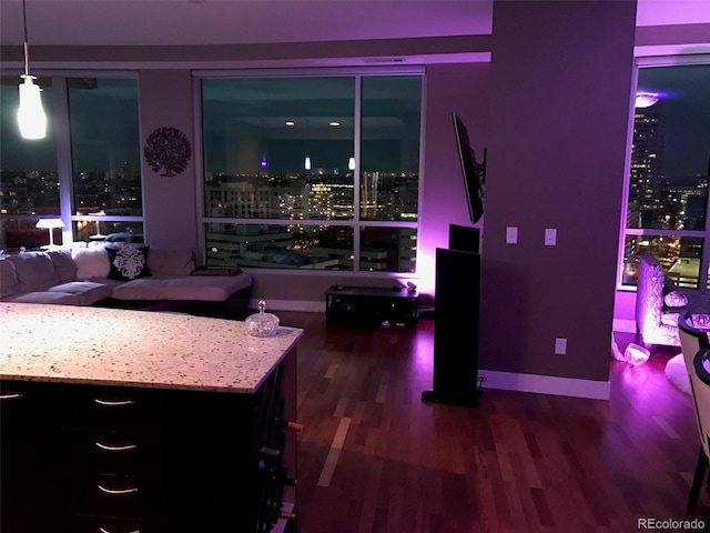 interior space with decorative light fixtures, light stone counters, and dark wood-type flooring