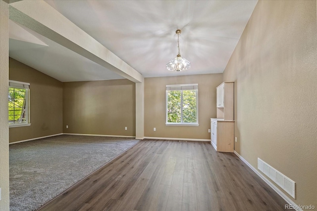 5932 S Versailles St, Aurora, CO 80015 - spare room featuring dark wood finished floors, a chandelier, plenty of natural light, and vaulted ceiling