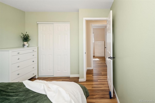 bedroom with wood finished floors, baseboards, and a closet