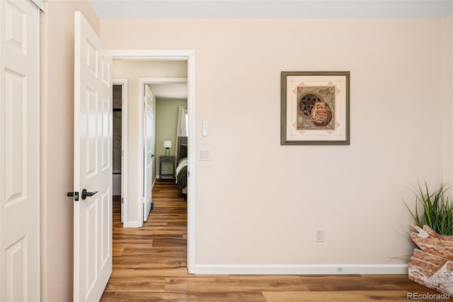 hallway with light wood-type flooring and baseboards