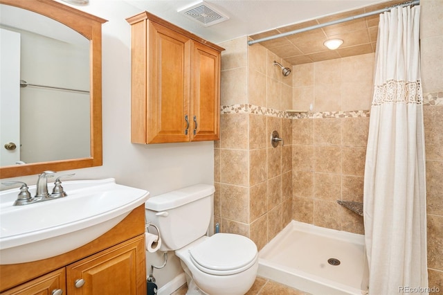 bathroom with a shower stall, vanity, visible vents, and toilet