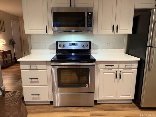 kitchen featuring stainless steel appliances, light wood-style flooring, white cabinetry, and backsplash