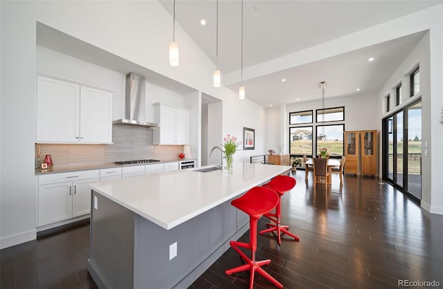 8765 Canyon Wind St, Parker, CO 80138 - kitchen with wall chimney exhaust hood, a large island, decorative backsplash, dark wood-style floors, and recessed lighting