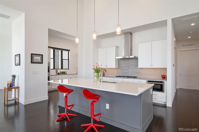 8765 Canyon Wind St, Parker, CO 80138 - kitchen with wall chimney exhaust hood, decorative backsplash, light countertops, dark wood-style floors, and recessed lighting