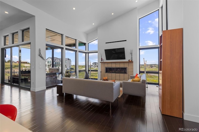 8765 Canyon Wind St, Parker, CO 80138 - living area with a glass covered fireplace, a towering ceiling, recessed lighting, plenty of natural light, and dark wood-style flooring