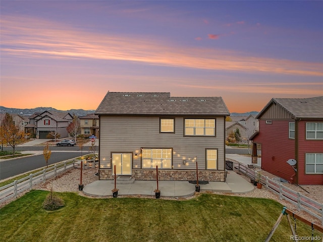 back house at dusk with a yard and a patio area