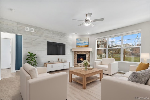 living room with light hardwood / wood-style floors, wooden walls, and ceiling fan