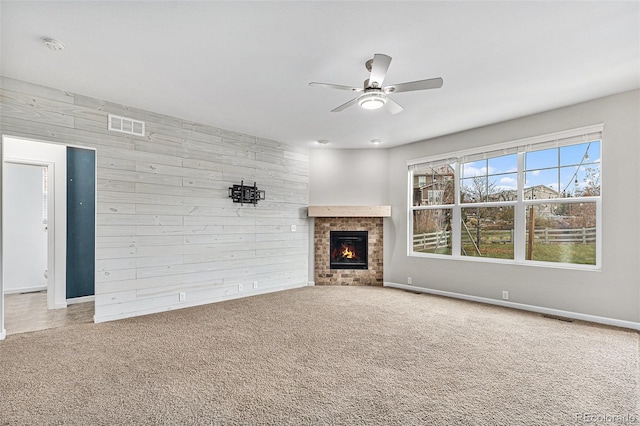 unfurnished living room with wooden walls, carpet flooring, and ceiling fan