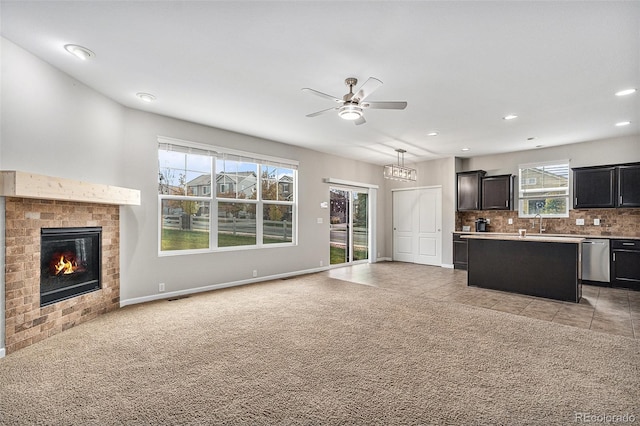 unfurnished living room featuring a brick fireplace, light colored carpet, and a healthy amount of sunlight