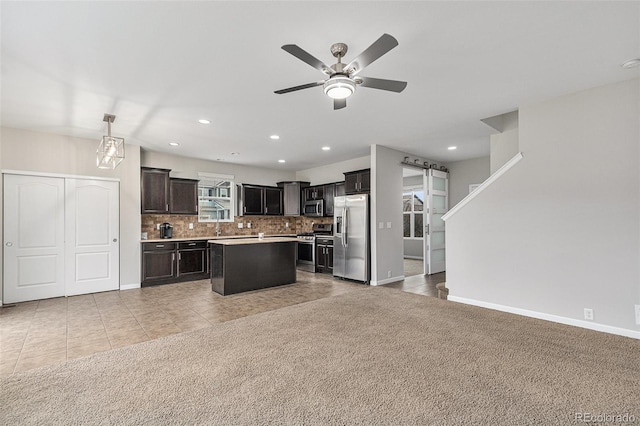 kitchen featuring light carpet, appliances with stainless steel finishes, tasteful backsplash, a kitchen island, and pendant lighting