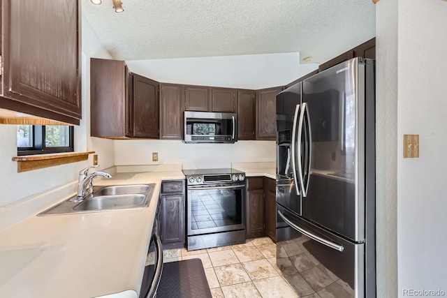 kitchen with a sink, light countertops, dark brown cabinets, appliances with stainless steel finishes, and a textured ceiling