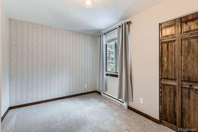 unfurnished bedroom with carpet floors, an accent wall, baseboards, and a baseboard radiator