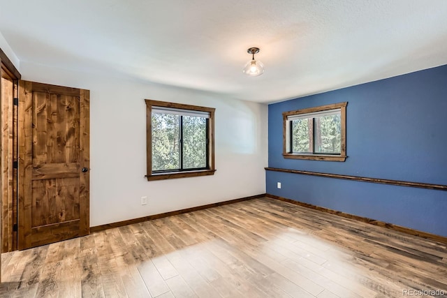 unfurnished room with baseboards and wood finished floors