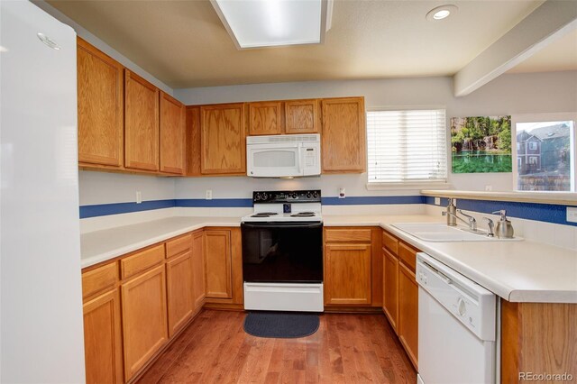 kitchen featuring beamed ceiling, white appliances, sink, and light hardwood / wood-style flooring