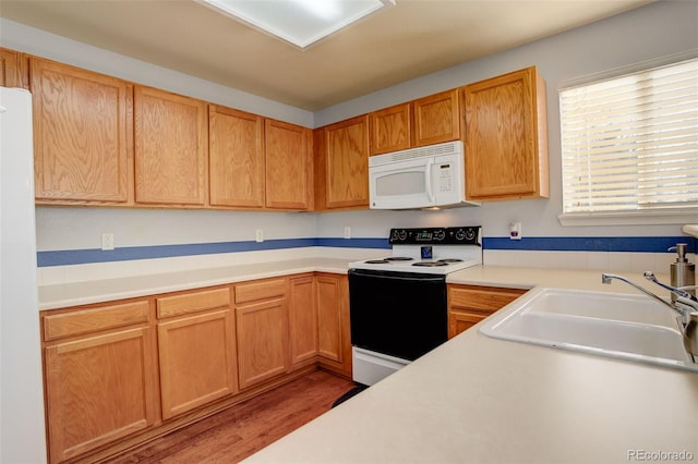 kitchen with sink, white appliances, and hardwood / wood-style flooring