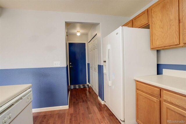 kitchen featuring white appliances and dark hardwood / wood-style flooring