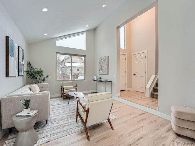 living room featuring light wood-type flooring and high vaulted ceiling